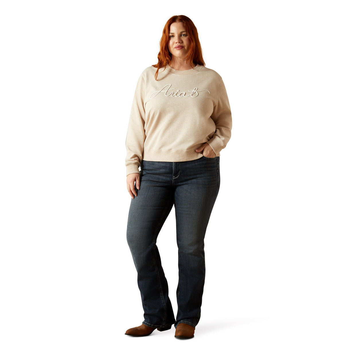 Woman wearing a beige sweater and dark jeans on a white background