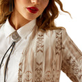 Close-up of a person wearing a patterned shirt with a bolo tie against a white background