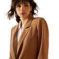Woman wearing a brown blazer over a white shirt on a white background