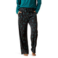 Person wearing black patterned pajama pants with a teal top on a white background