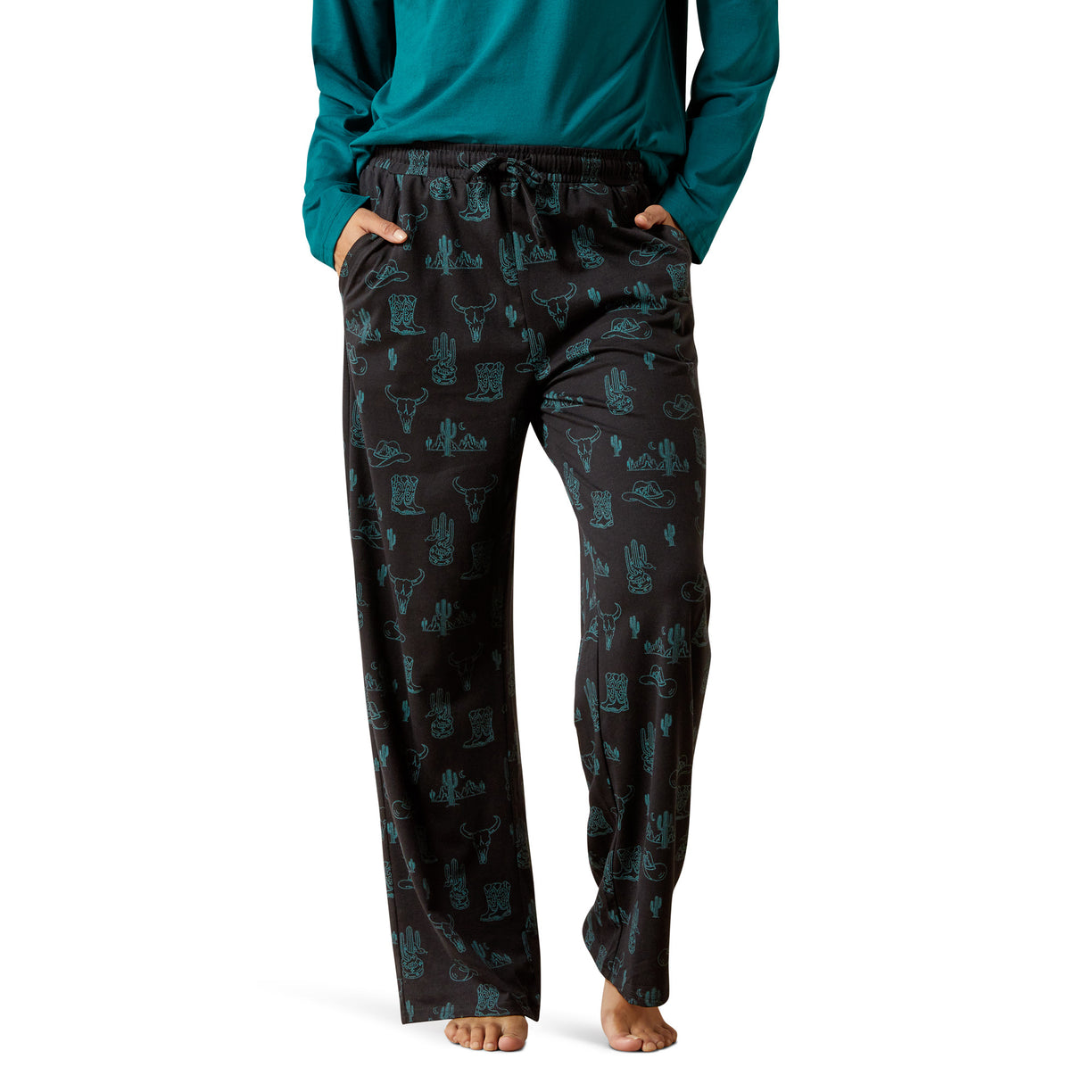 Person wearing black patterned pajama pants with a teal top on a white background
