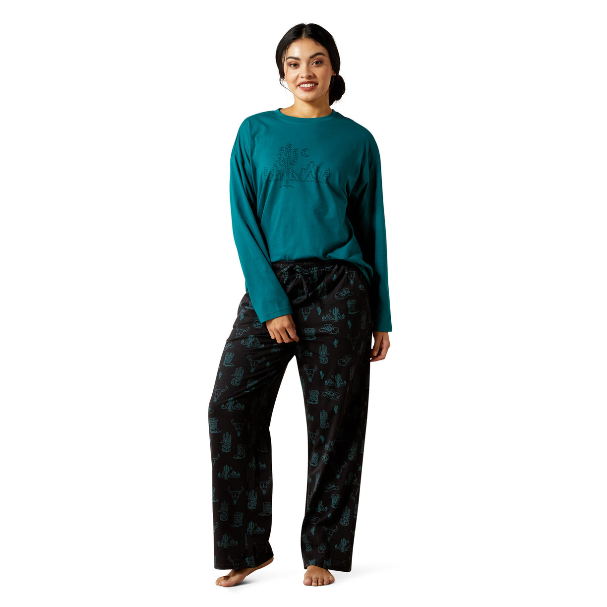 Woman wearing teal long-sleeve top and dark patterned pants on a white background