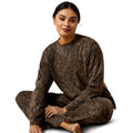 Woman wearing a brown patterned outfit sitting on a white background