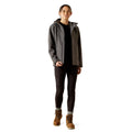 Person wearing a gray jacket with a hood, black pants, and brown boots on a white background