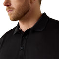 Close-up of a person wearing a black polo shirt with a brand logo on a white background