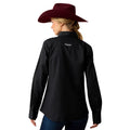 Person wearing a black shirt with a logo on the back, standing against a white background