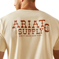 Man wearing a beige t-shirt with 'Ariat Supply' logo on the back, standing against a white background.