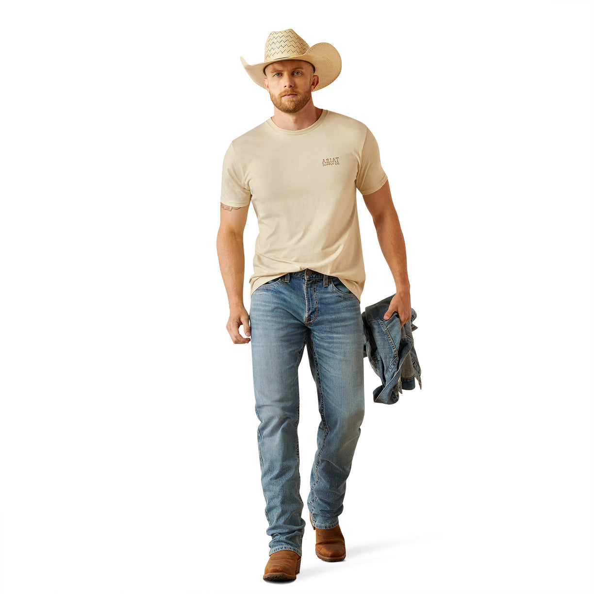 Man wearing a beige t-shirt with 'Ariat Supply' logo on the back, standing against a white background.