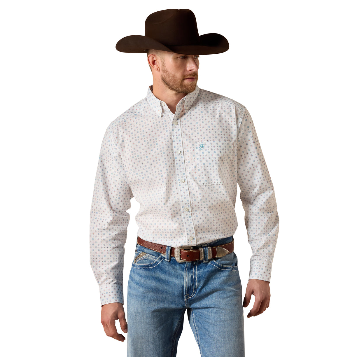 A man wearing a white long-sleeve western shirt with a small blue and red geometric pattern, paired with blue jeans, a brown belt, and a dark brown cowboy hat, shown against a plain white background.