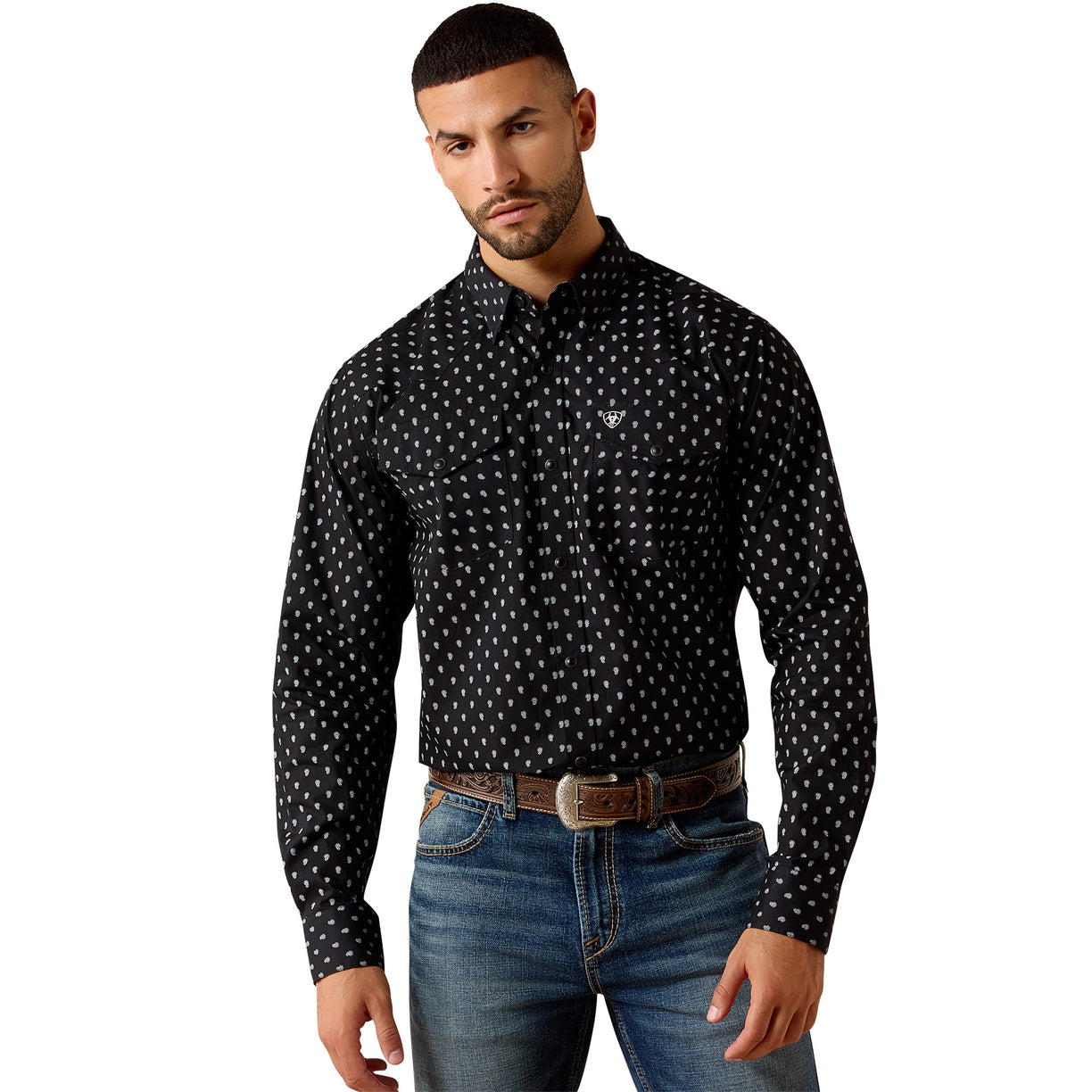 Man wearing a black patterned shirt and blue jeans on a beige background