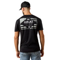 Man wearing a black t-shirt with Ariat logo on the back against a beige background