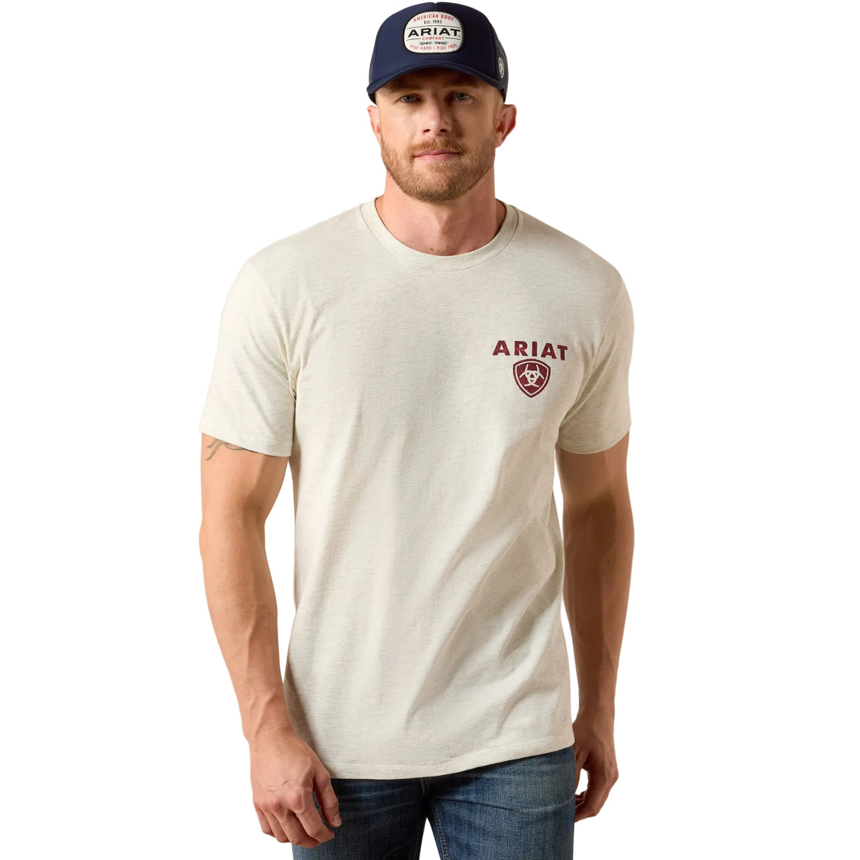 Man wearing a white t-shirt with Ariat logo and a matching cap on a beige background