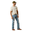 Man wearing a white t-shirt, blue jeans, and a green cap against a plain background