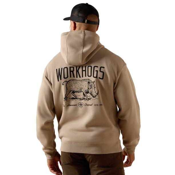 A man viewed from behind wearing a beige pullover hoodie with a large black graphic on the back featuring the word 'WORKHOGS' and an illustration of a boar. He is also wearing a black baseball cap and brown pants, set against a plain white background.