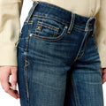 Close-up of blue jeans with a beige shirt worn by a person on a white background