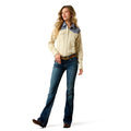 Woman wearing a beige shirt with denim accents and blue jeans on a white background