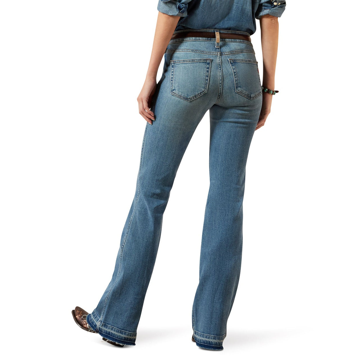Woman wearing a denim shirt and jeans with a beige hat on a white background