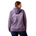 A woman shown from the back wearing a lavender-purple hoodie with a white 'Ariat' logo printed across the back, paired with dark blue jeans against a plain white background.