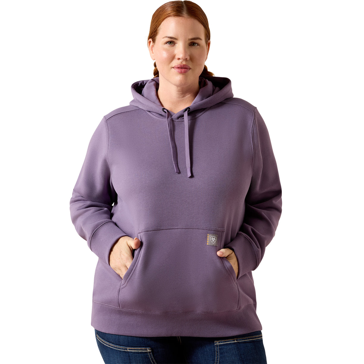 A woman wearing a dusty purple pullover hoodie with drawstrings and a kangaroo pocket, paired with blue jeans, against a plain white background.