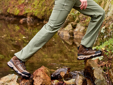 Woman hiker wearing new Ariat Traverse Hiking Boots and Pants crossing a creek.