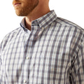 Close-up of a man wearing a plaid shirt with a visible brand logo.