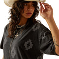 Woman wearing a black patterned top and straw hat on a white background