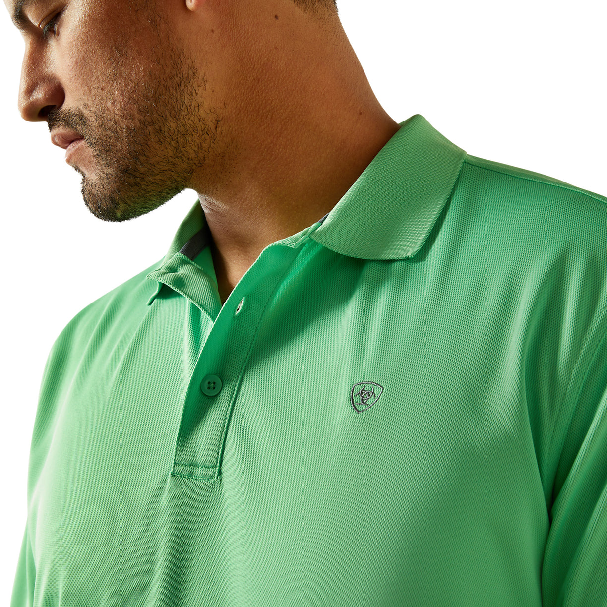 Close-up of a person wearing a green polo shirt with a brand logo.