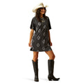 Woman wearing a patterned dress, cowboy boots, and a hat on a white background