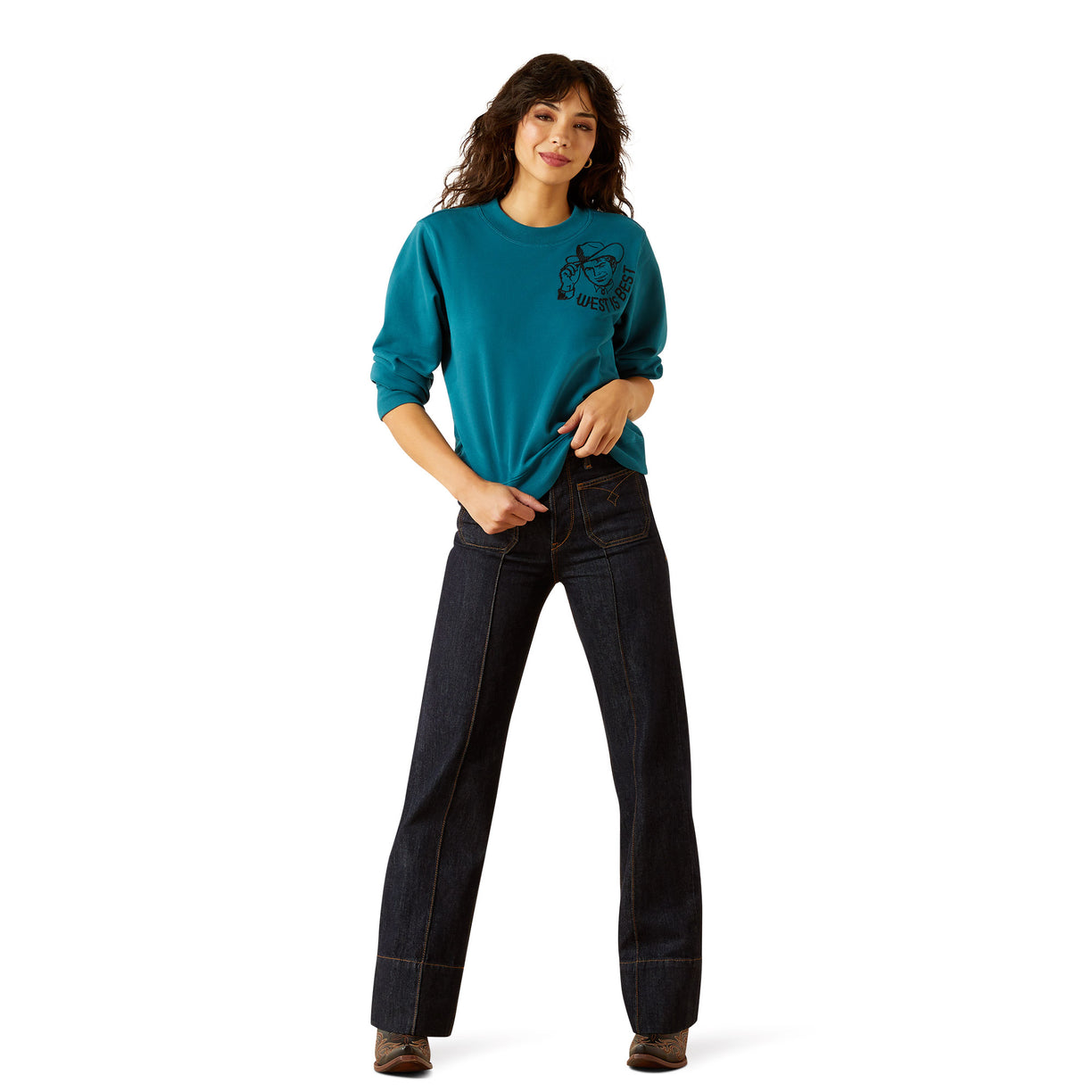 Woman wearing a teal sweatshirt and dark jeans on a white background