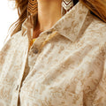 Close-up of a person wearing a patterned shirt with fringe earrings.