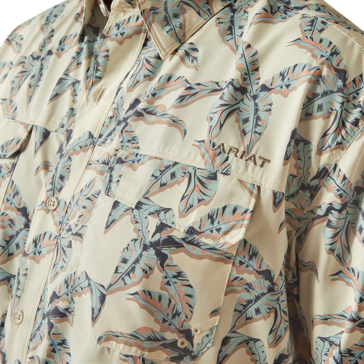 Beige shirt with tropical leaf pattern and 'WAT' branding on a beige background