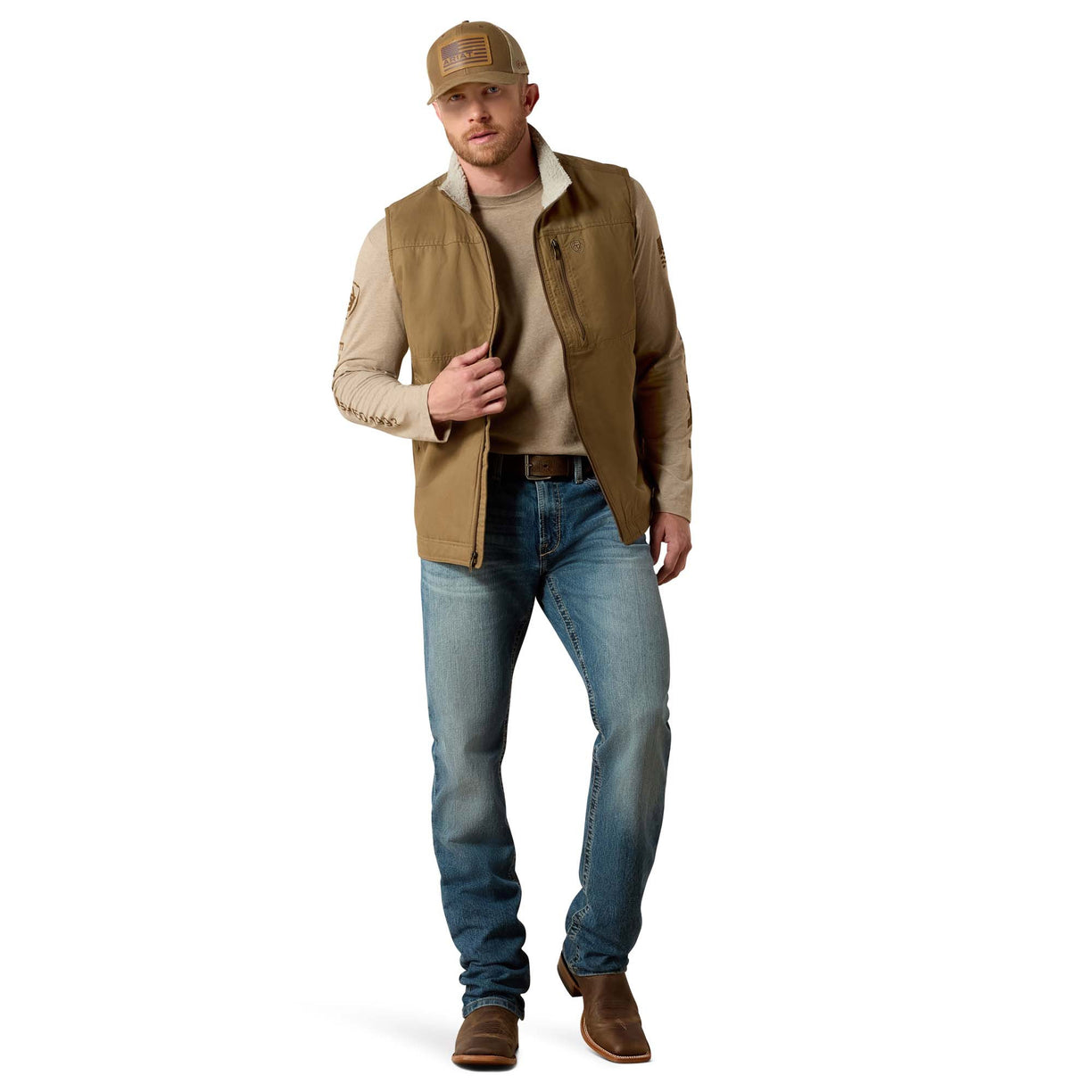 Man wearing a brown vest, beige shirt, blue jeans, and brown boots on a white background